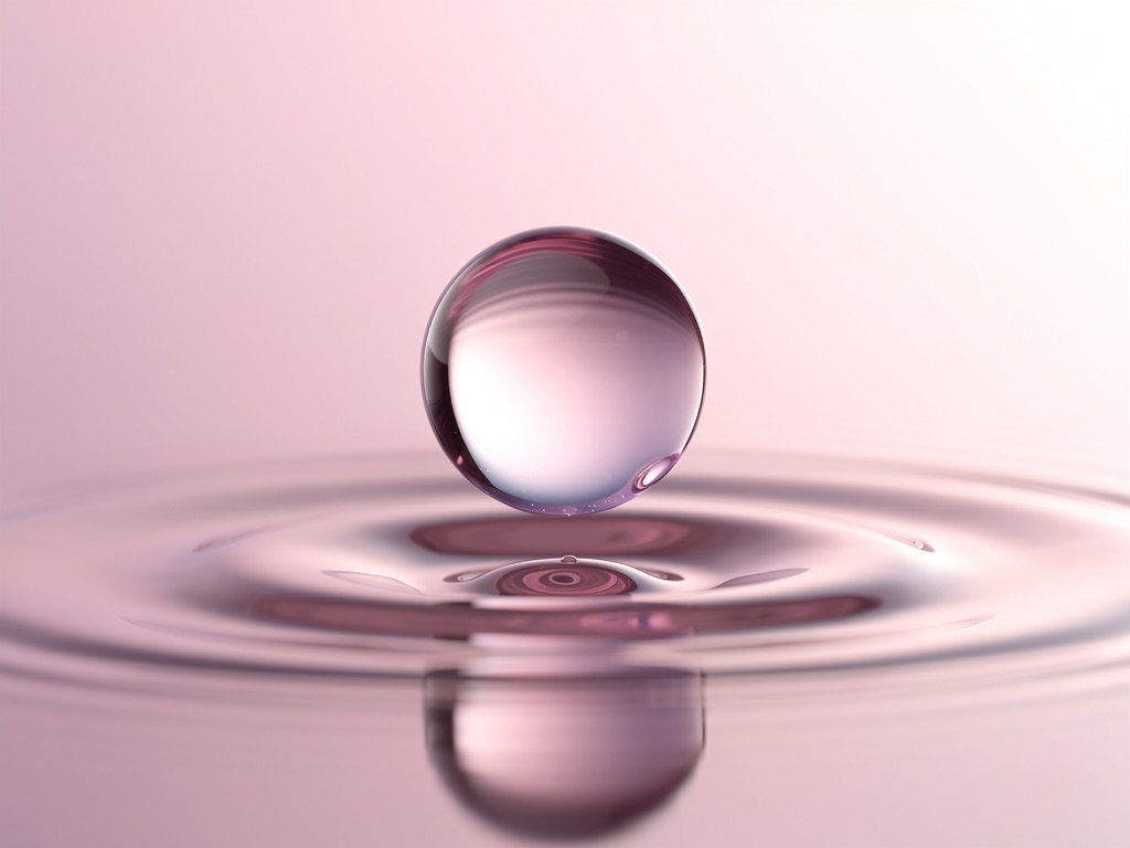 A pink lilac liquid drop above soft ripples