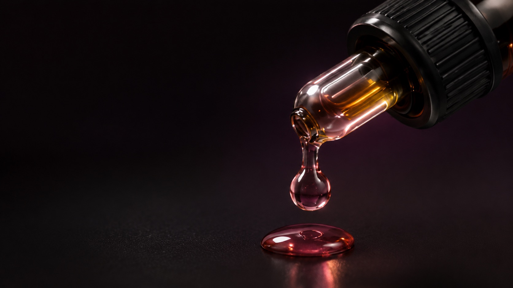 A rose-tinted drop falling from the Amplify glass dropper