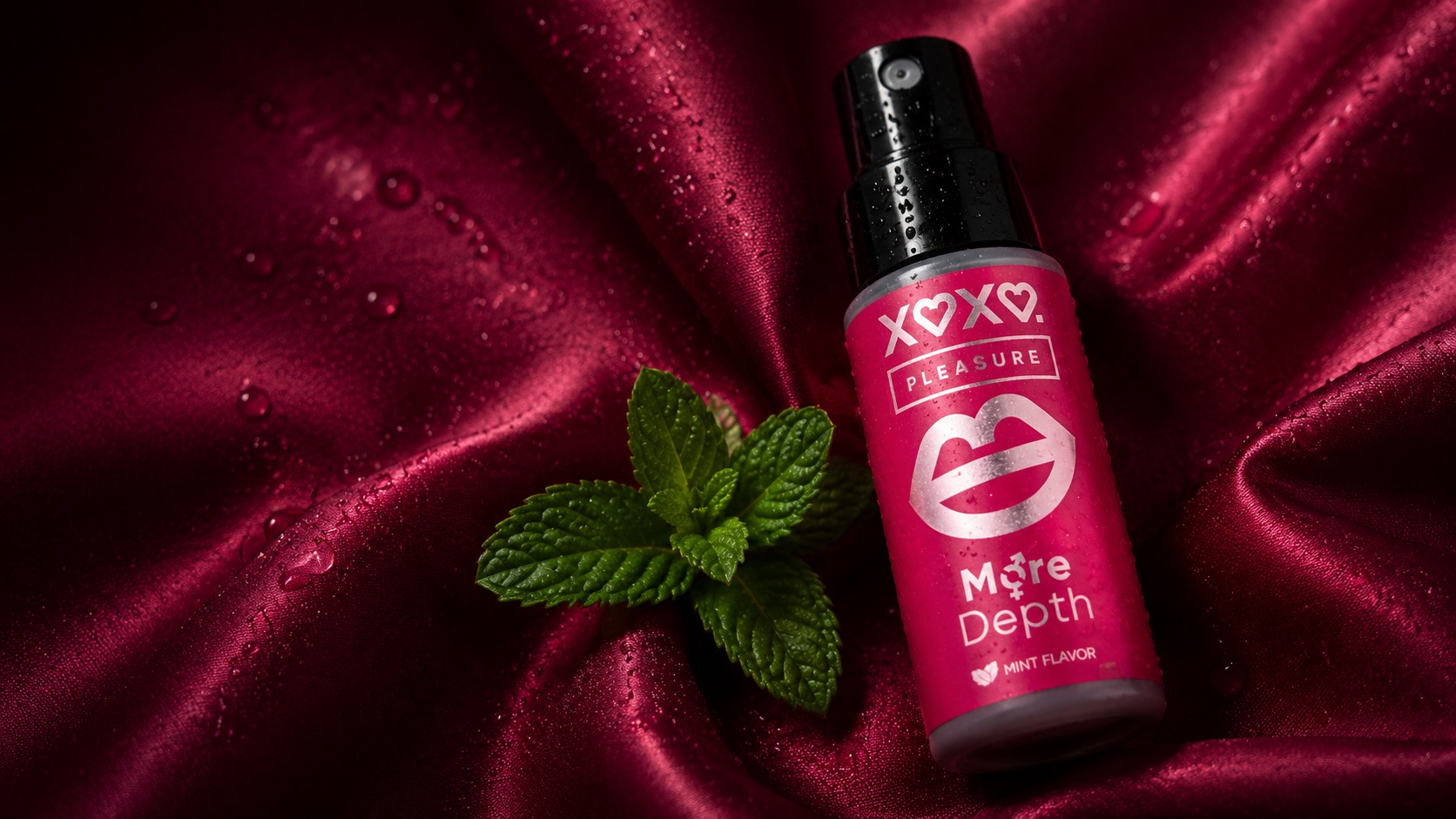 Pleasure spray bottle with fresh mint on wet raspberry satin